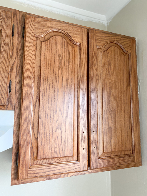 Learn how to freshen up kitchen cabinets without paint! Transform outdated cabinets with deep cleaning, stain + poly application for a budget-friendly makeover.